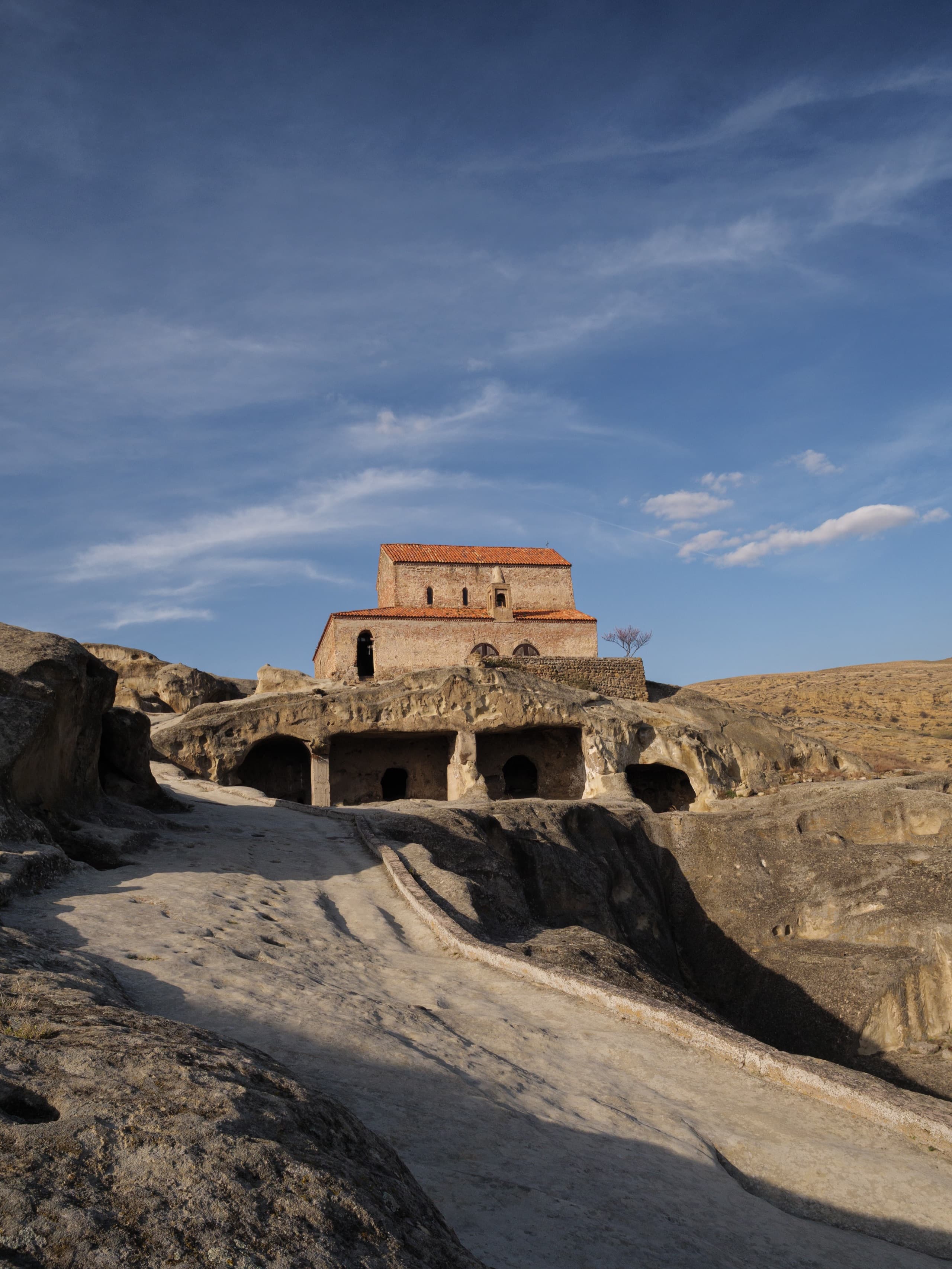 Ancient cave city of Uplistsikhe carved from living rock with Christian church perched above cave dwellings
