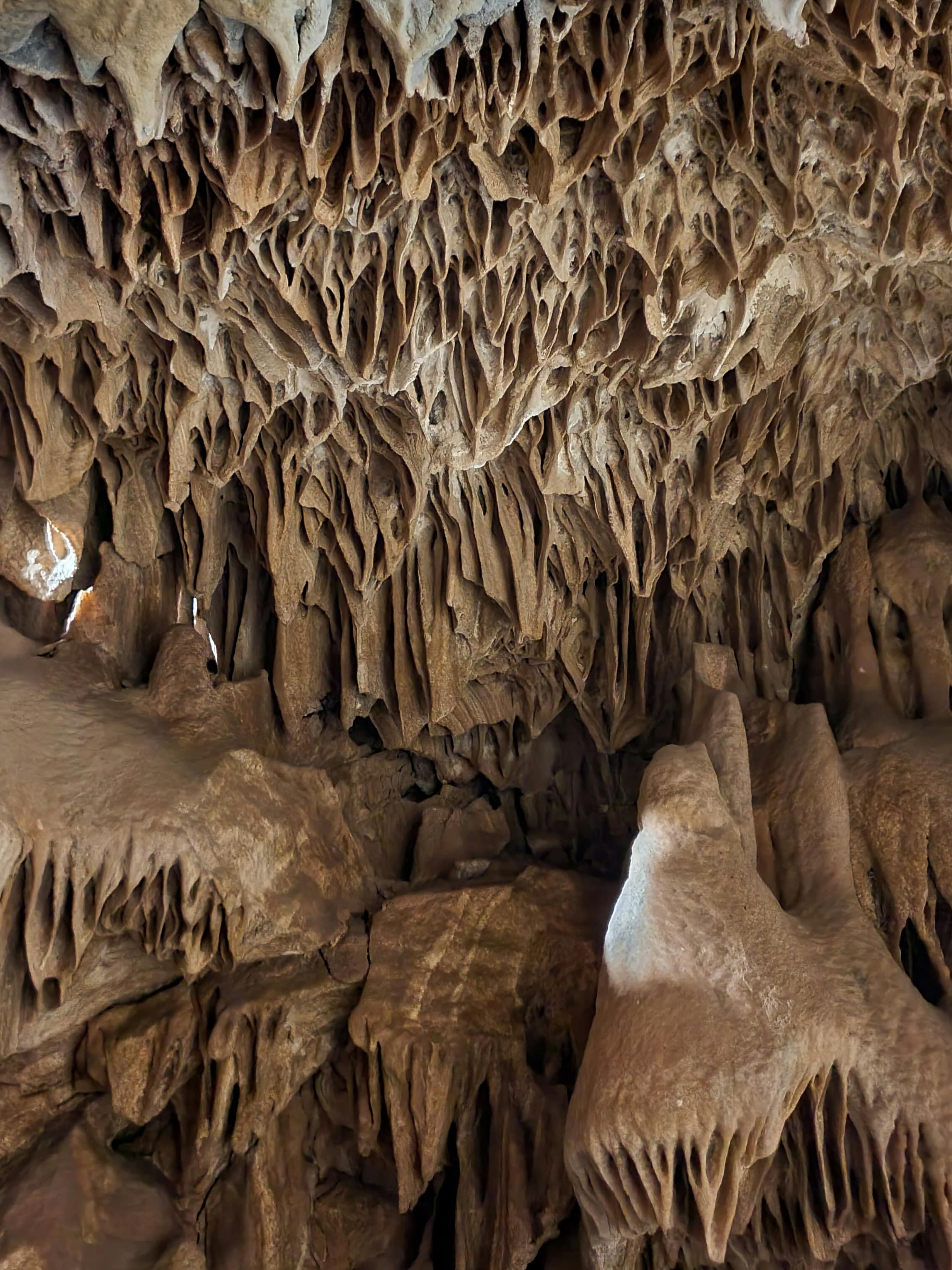 Interior of Prometheus Cave showing impressive stalactite and stalagmite formations with underground lighting