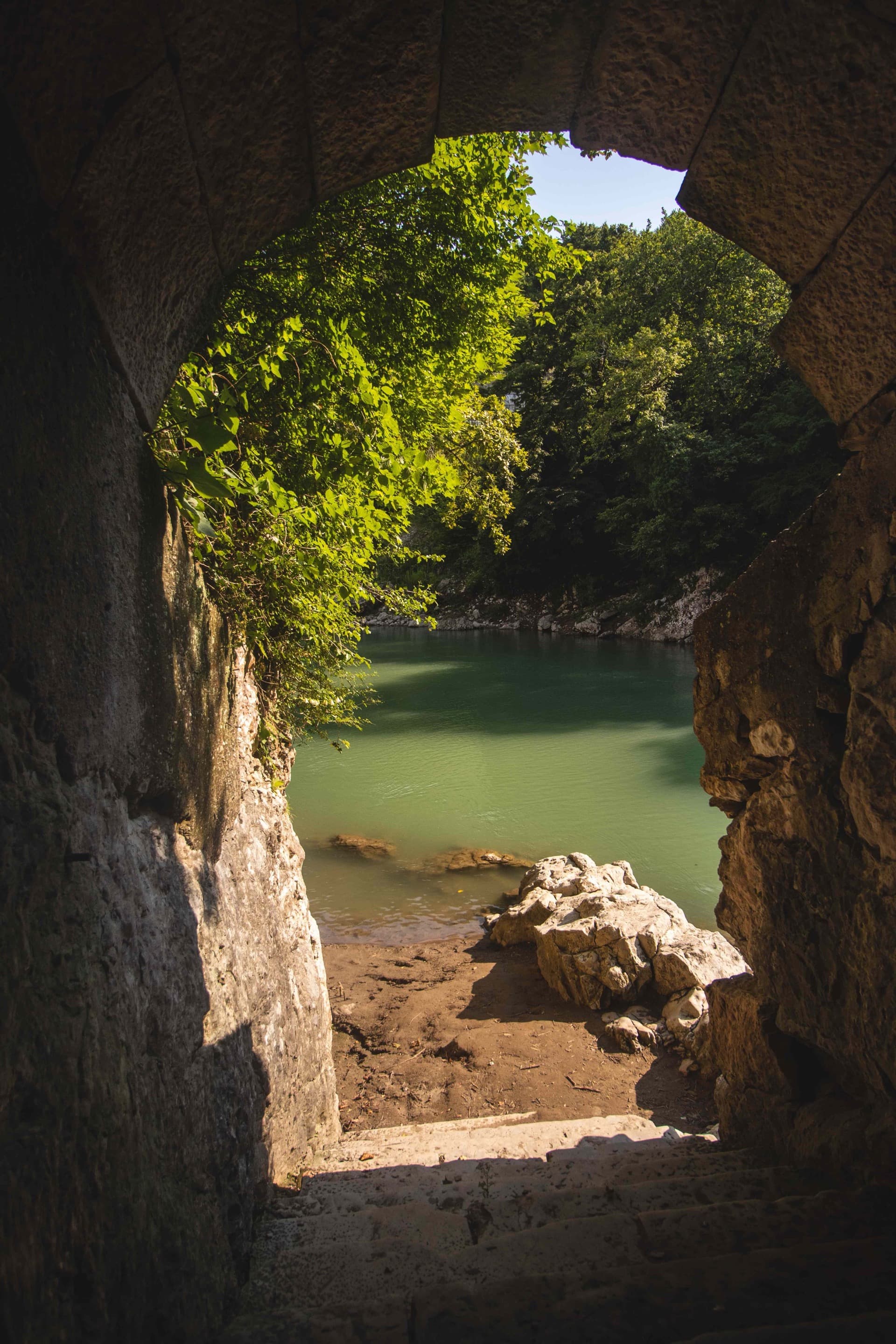 View through ancient stone ruins of Nokalakevi fortress looking out to turquoise river and canyon landscape