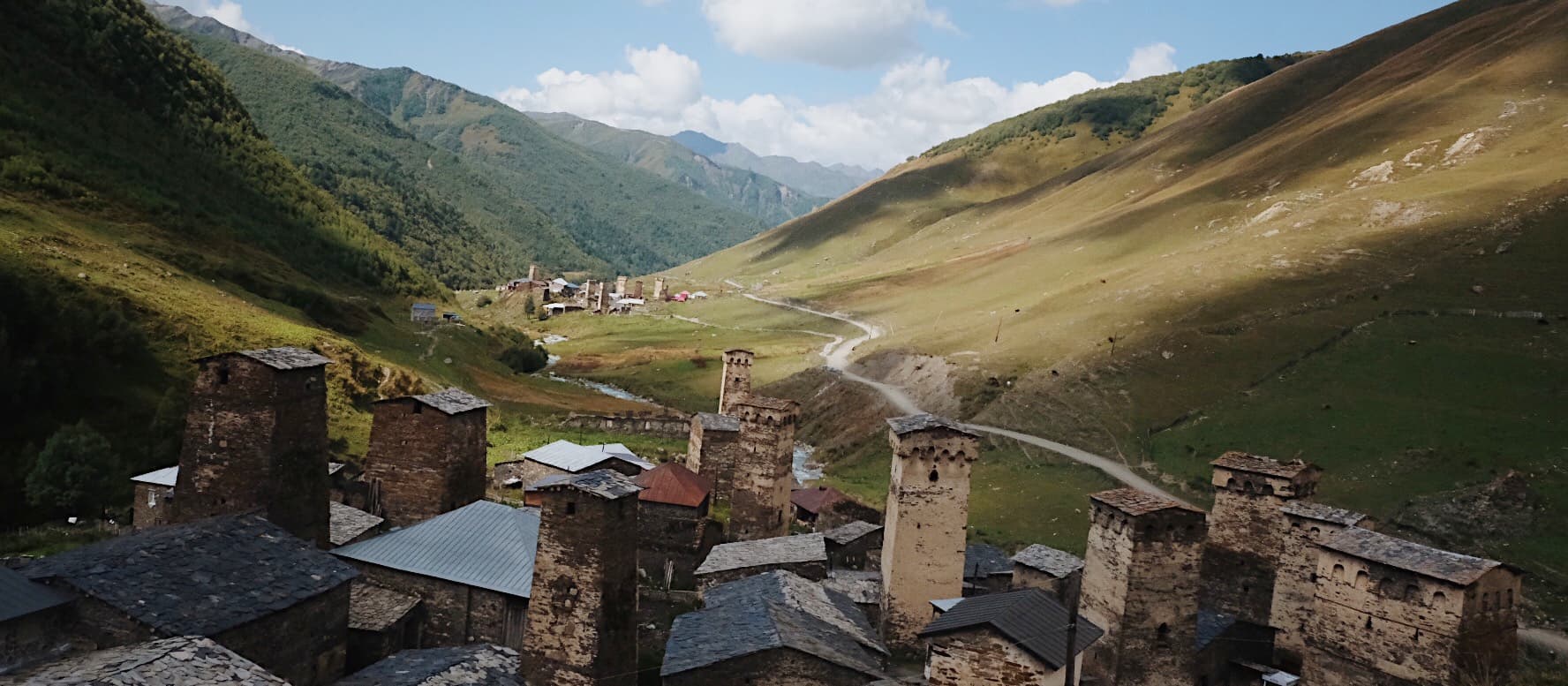 Medieval Svanetian defensive towers in UNESCO-protected Ushguli village with snow-capped Caucasus peaks in background
