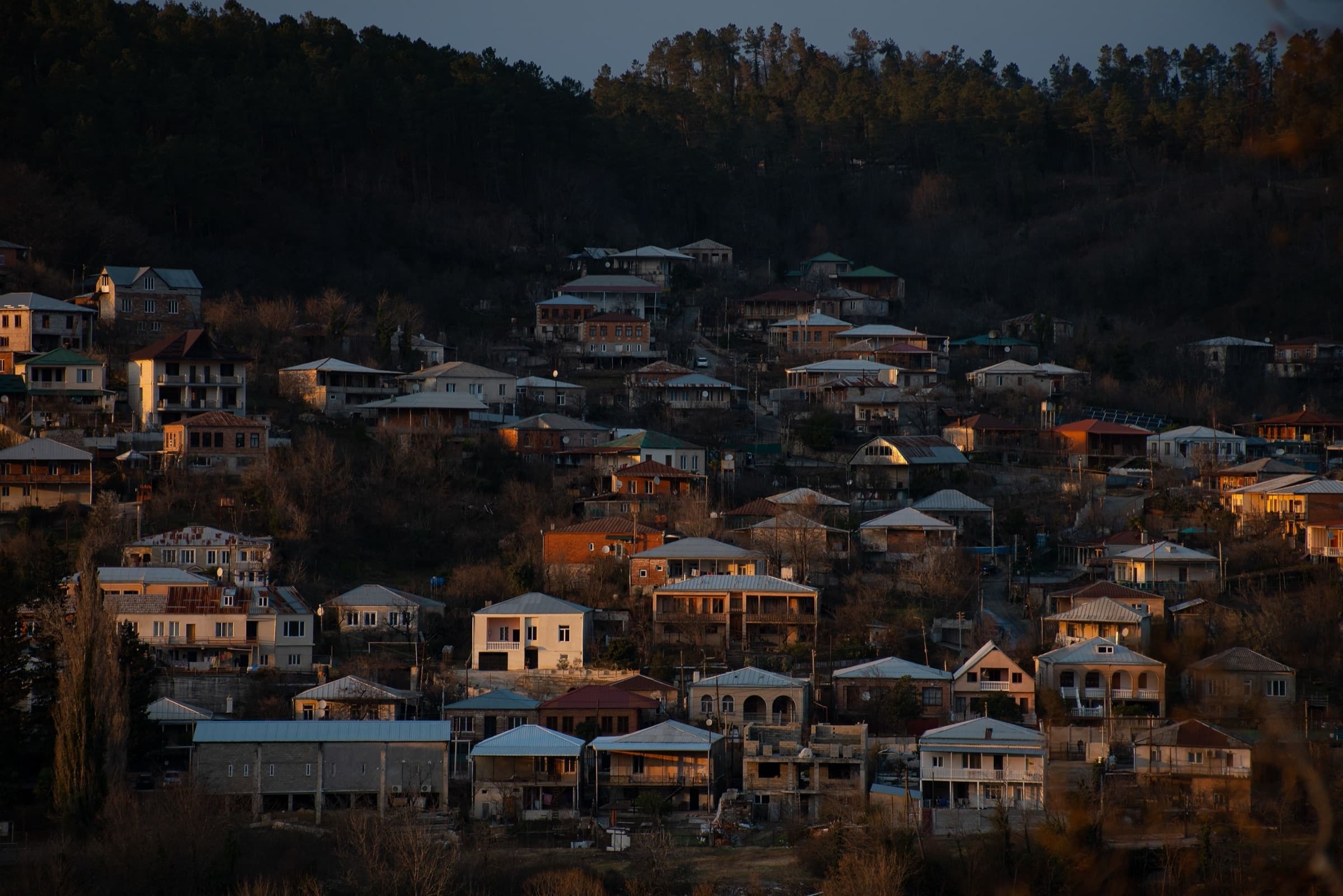 Kutaisi - A Personal Wander Through Georgia's City of Poetry Hillside houses in Kutaisi catching golden sunset light against a dark forested ridge
